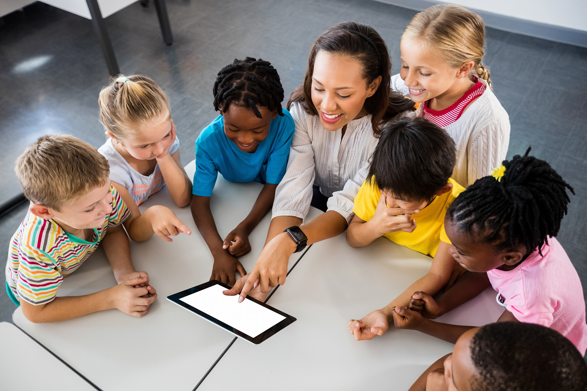 Teachers showing children in a group an image on a pad