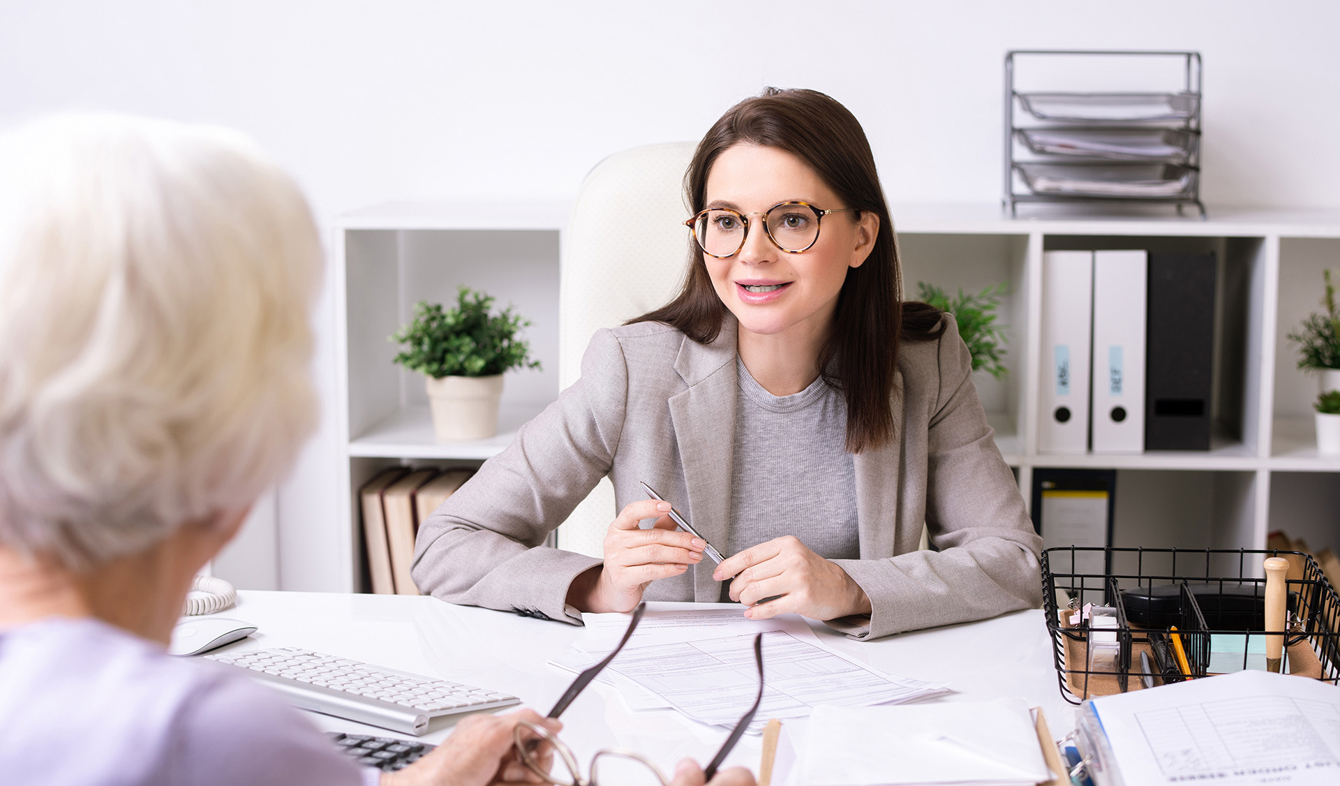 Social worker sitting at a desk and talking to senior lady