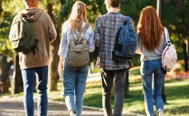 Four students with backpacks walking away